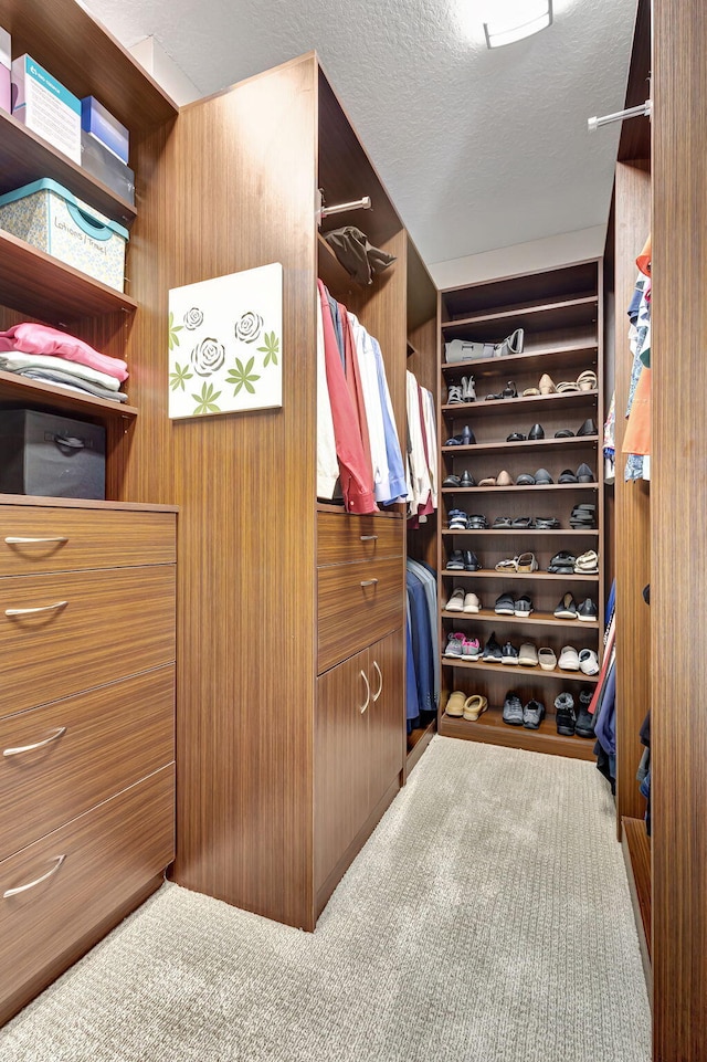 walk in closet featuring light colored carpet