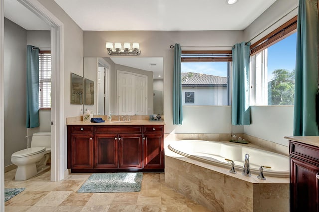 bathroom featuring vanity, tiled bath, and toilet