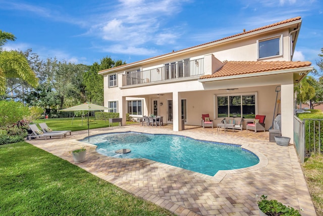 rear view of house with a patio, a balcony, outdoor lounge area, a yard, and ceiling fan