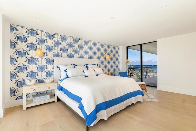 bedroom with hardwood / wood-style flooring, access to exterior, and expansive windows