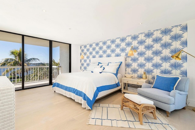 bedroom with hardwood / wood-style flooring, expansive windows, and access to outside