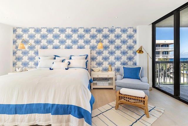 bedroom with wood-type flooring, expansive windows, and access to outside