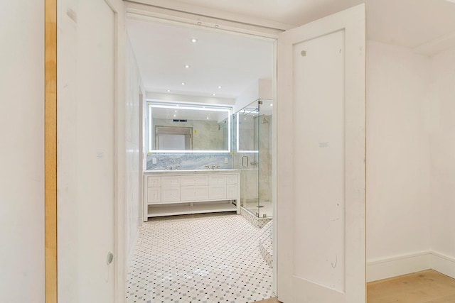 bathroom featuring a shower with door, decorative backsplash, and vanity