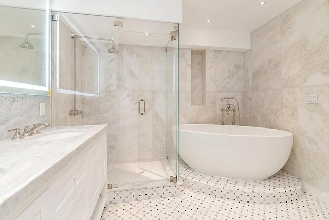 bathroom featuring plus walk in shower, tile patterned flooring, vanity, and tile walls