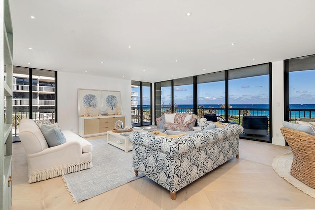 living room featuring a water view, a wall of windows, and light hardwood / wood-style flooring