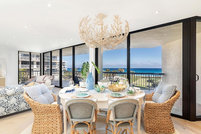 dining area with floor to ceiling windows, a water view, and an inviting chandelier