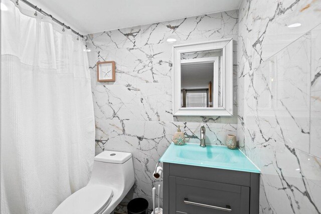 bathroom with vanity, curtained shower, tile walls, and toilet