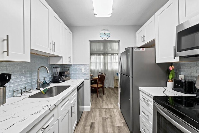 5219 NE 20th Ter, Pompano Beach, FL 33064 - kitchen featuring white cabinets, a sink, light wood-type flooring, light stone countertops, and appliances with stainless steel finishes