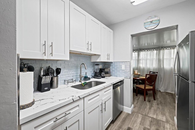 kitchen featuring white cabinetry, stainless steel appliances, sink, and light hardwood / wood-style flooring