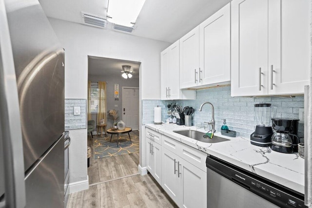 kitchen featuring appliances with stainless steel finishes, sink, white cabinets, and light stone counters