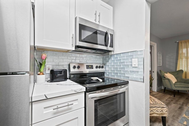 kitchen with stainless steel appliances, dark wood-type flooring, white cabinets, and decorative backsplash