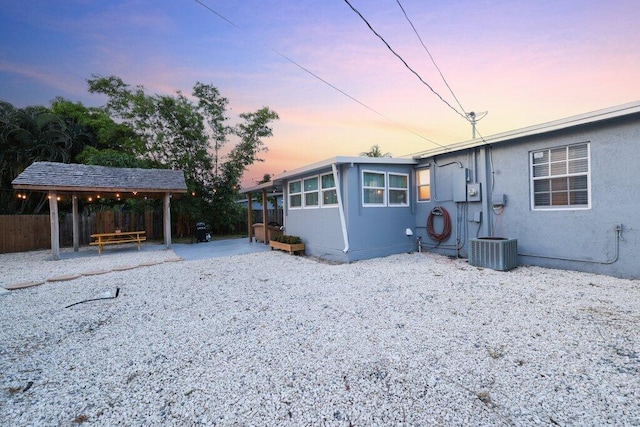 back house at dusk with central AC unit and a patio area