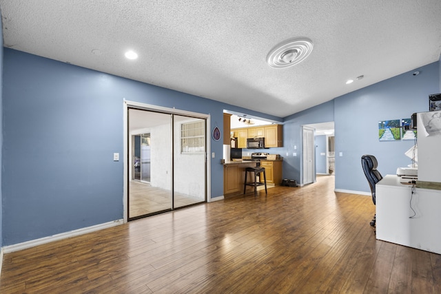 interior space featuring wood-type flooring, a textured ceiling, and vaulted ceiling