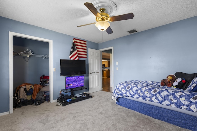 carpeted bedroom featuring ceiling fan, a closet, and a textured ceiling