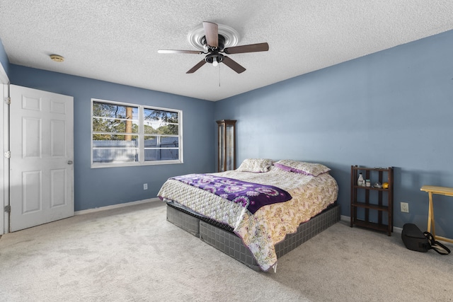 bedroom featuring ceiling fan, light carpet, and a textured ceiling