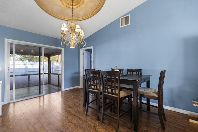 dining space featuring dark wood-type flooring, lofted ceiling, and a notable chandelier