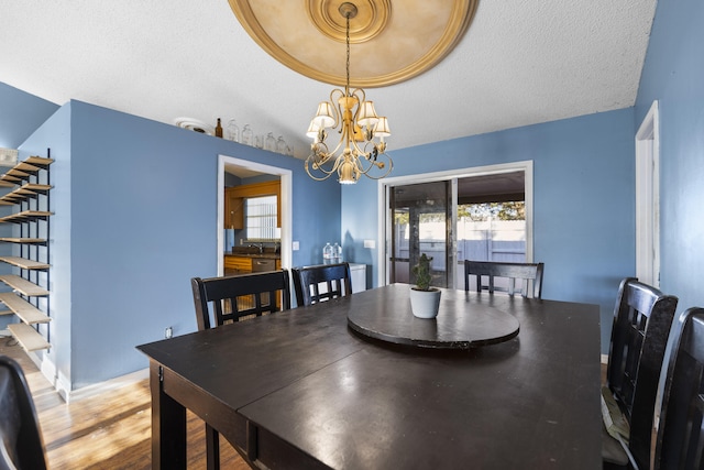 dining space featuring vaulted ceiling, an inviting chandelier, a textured ceiling, and hardwood / wood-style flooring