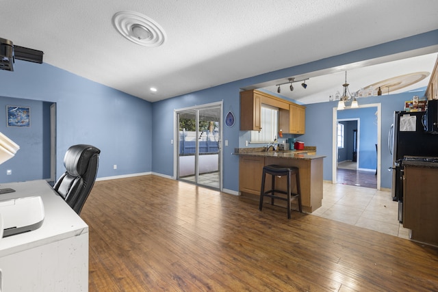 office space featuring a textured ceiling, vaulted ceiling, and hardwood / wood-style floors