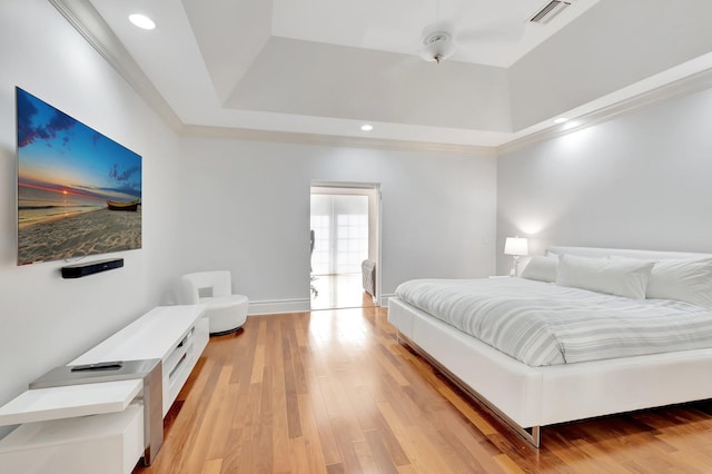 bedroom with a raised ceiling, ceiling fan, and light wood-type flooring