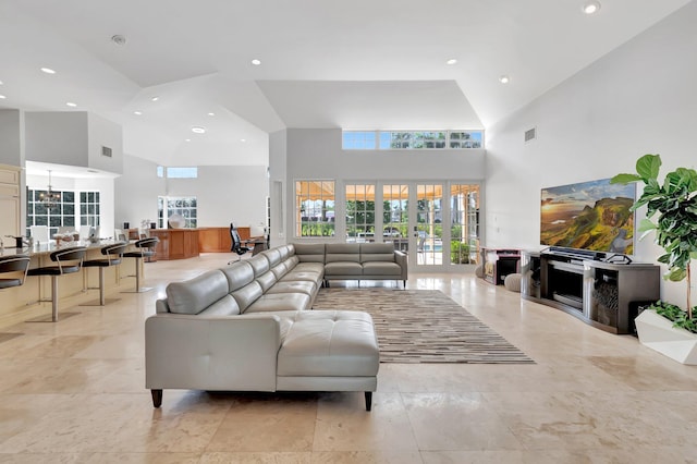 living room with a chandelier, a towering ceiling, and french doors