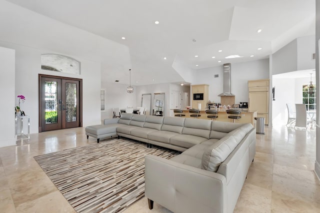 living room featuring a towering ceiling, a wealth of natural light, and french doors