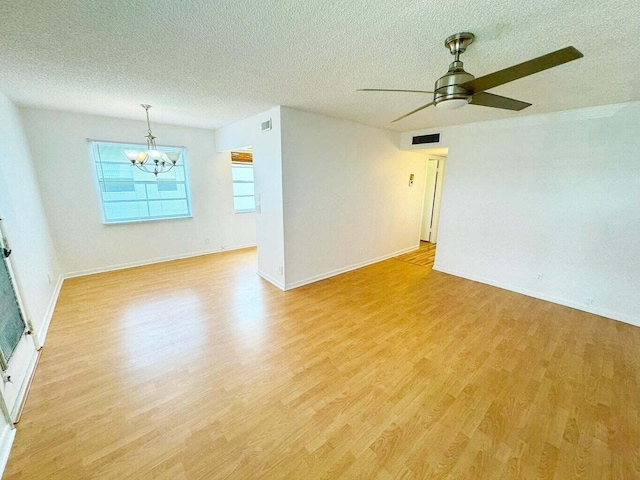 spare room featuring a textured ceiling, ceiling fan with notable chandelier, and light wood-type flooring