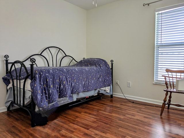 bedroom with multiple windows and dark wood-type flooring