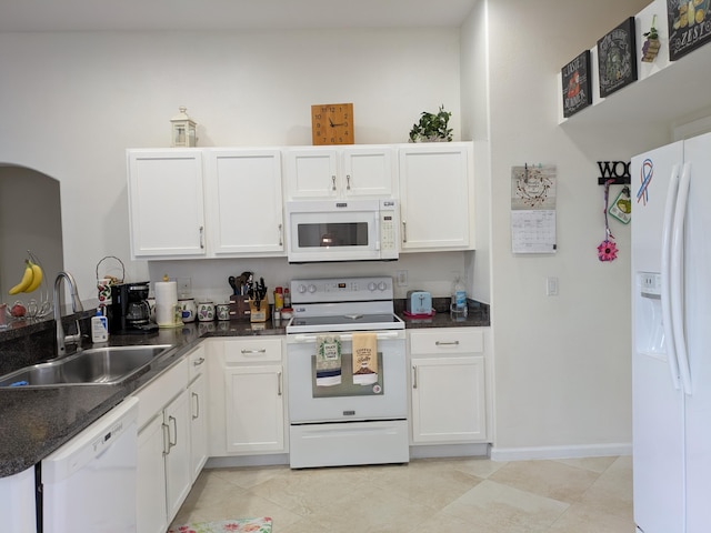 kitchen featuring light tile patterned flooring, sink, white appliances, dark stone counters, and white cabinets