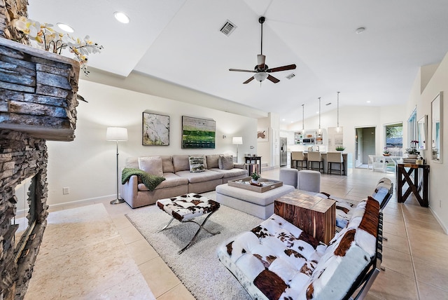 living room with ceiling fan, light tile patterned flooring, a stone fireplace, and lofted ceiling