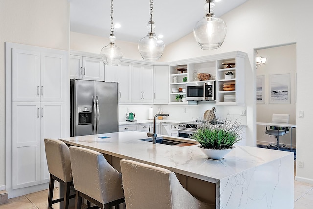 kitchen with a center island with sink, light stone counters, white cabinets, and stainless steel appliances