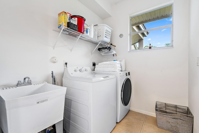 clothes washing area with washing machine and clothes dryer, sink, and light tile patterned floors