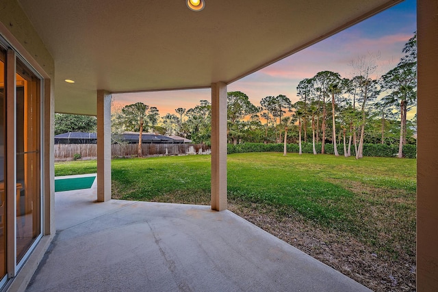 patio terrace at dusk featuring a yard