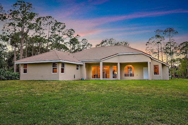 back house at dusk featuring a yard