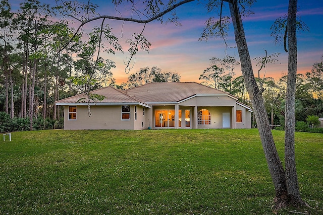 back house at dusk featuring a yard