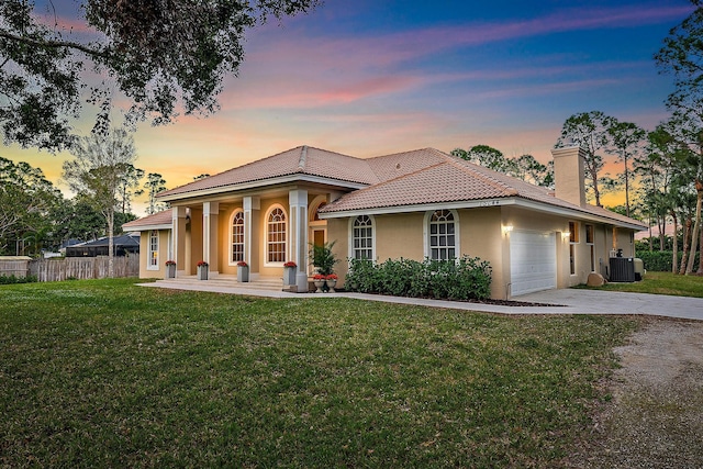 mediterranean / spanish-style house with covered porch, a yard, a garage, and cooling unit