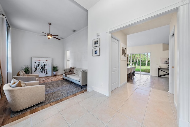 tiled living room featuring ceiling fan, crown molding, and vaulted ceiling