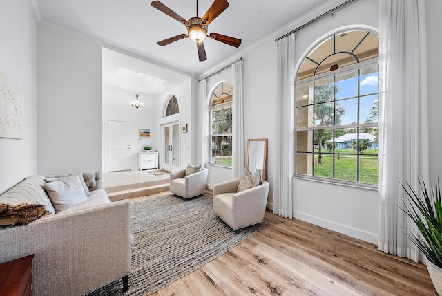 living room featuring crown molding, light hardwood / wood-style flooring, and ceiling fan with notable chandelier