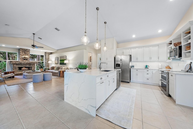 kitchen featuring an island with sink, white cabinets, stainless steel appliances, and lofted ceiling