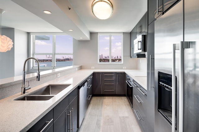 kitchen featuring light stone countertops, appliances with stainless steel finishes, sink, pendant lighting, and a water view