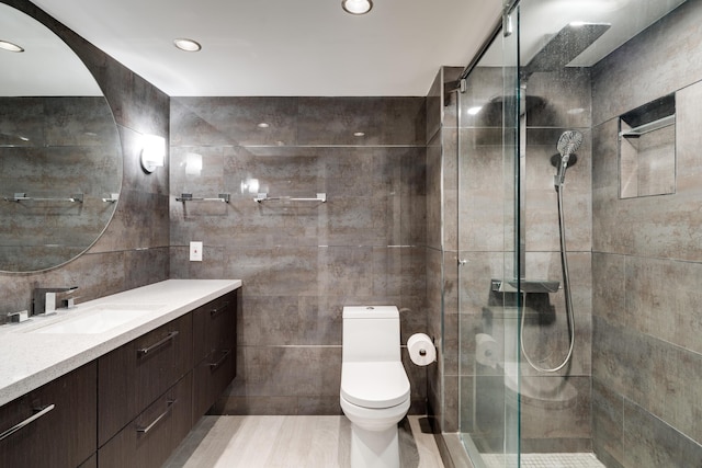 bathroom featuring vanity, toilet, a shower with door, and tile walls