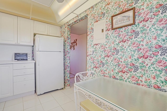 kitchen with white cabinets, white fridge, light tile patterned flooring, and electric panel