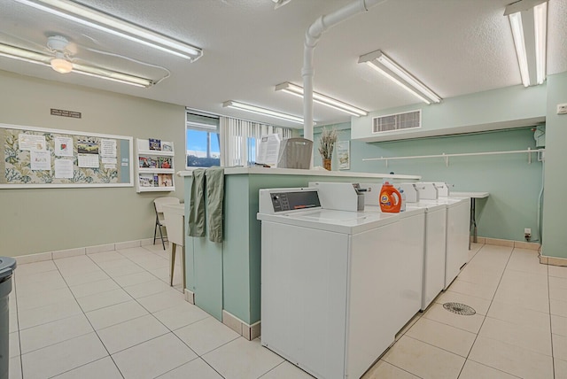 laundry area with separate washer and dryer, light tile patterned flooring, and a textured ceiling