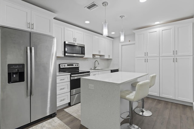 kitchen with dark wood-style floors, appliances with stainless steel finishes, light countertops, and a sink