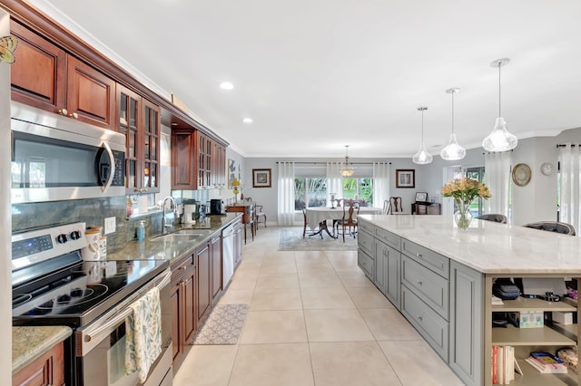 kitchen featuring light stone counters, pendant lighting, glass insert cabinets, appliances with stainless steel finishes, and a sink