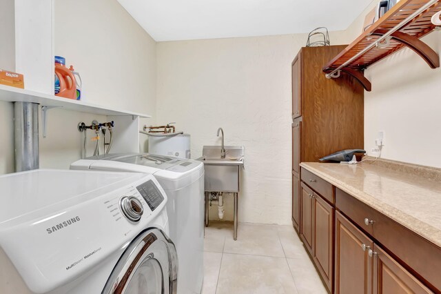 washroom with cabinet space, washer and clothes dryer, water heater, a sink, and light tile patterned flooring