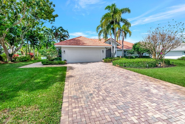 view of front of home featuring a garage, a tiled roof, decorative driveway, a front lawn, and stucco siding