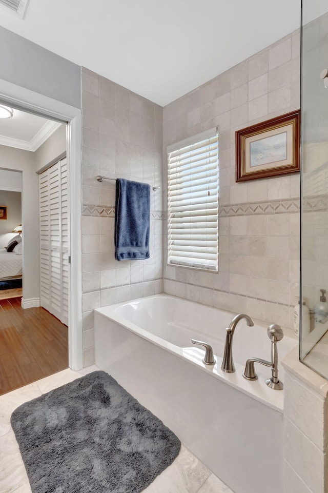 full bath featuring ensuite bathroom, ornamental molding, tile walls, and a bath