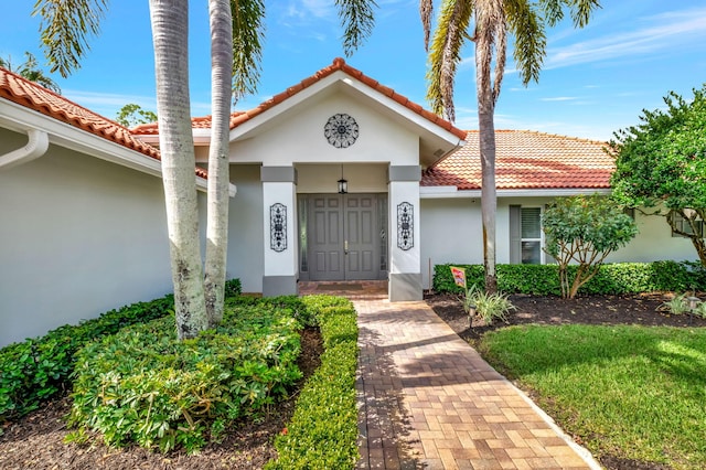 entrance to property with a tiled roof and stucco siding