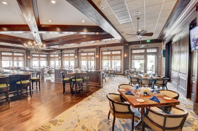 dining area with ceiling fan with notable chandelier, beam ceiling, coffered ceiling, and wood finished floors