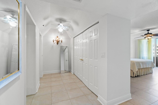 hallway featuring vaulted ceiling, light tile patterned floors, and a textured ceiling